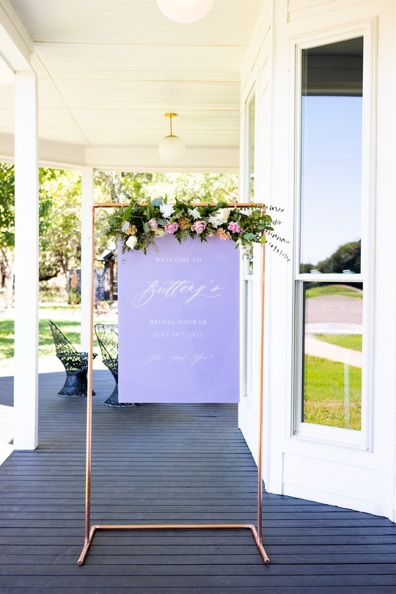 Purple bridal shower sign by Lily & Roe Co. hanging from a rose gold minimalist frame