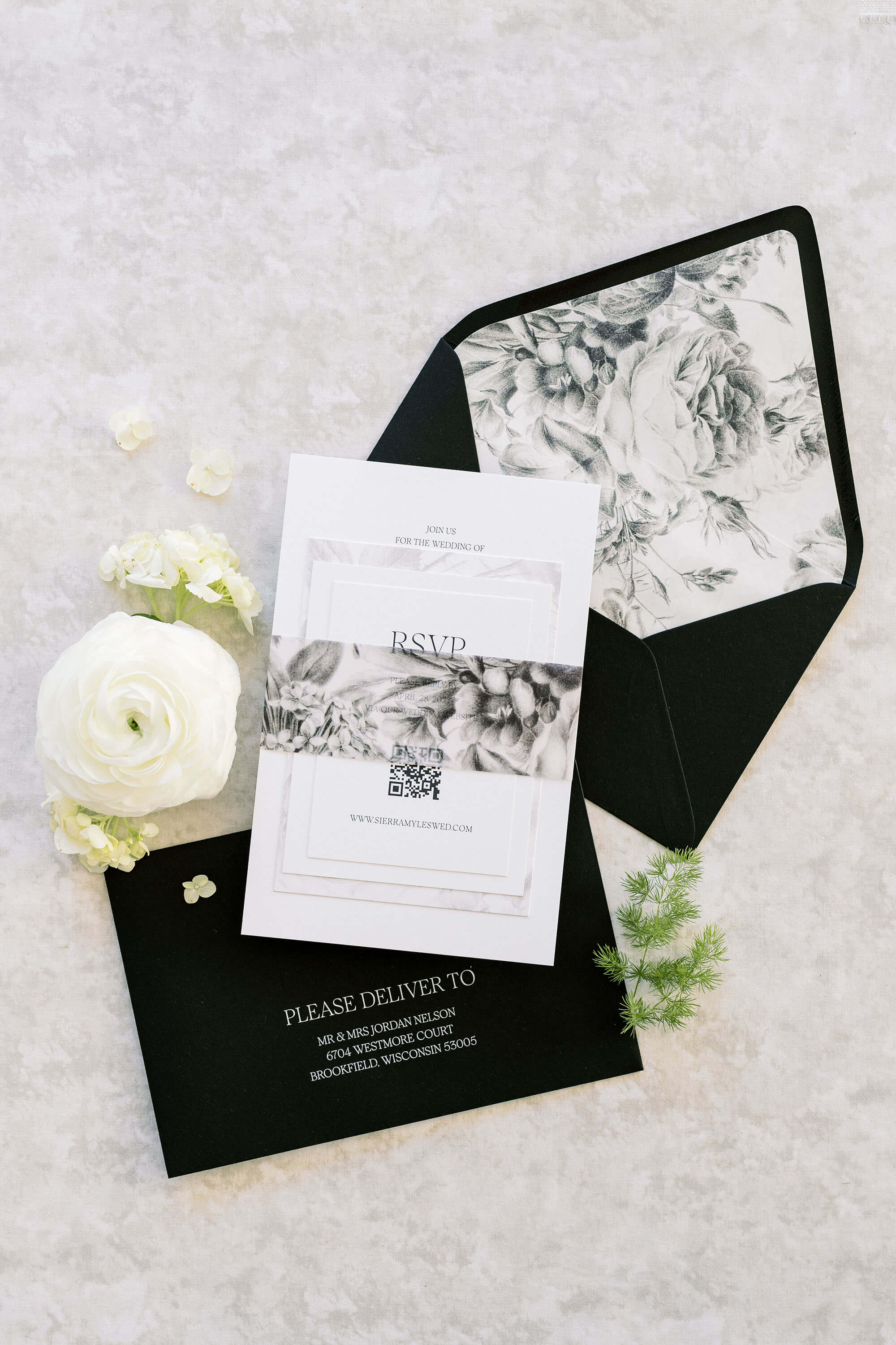 Black and white wedding invitation set with RSVP card on a textured surface.