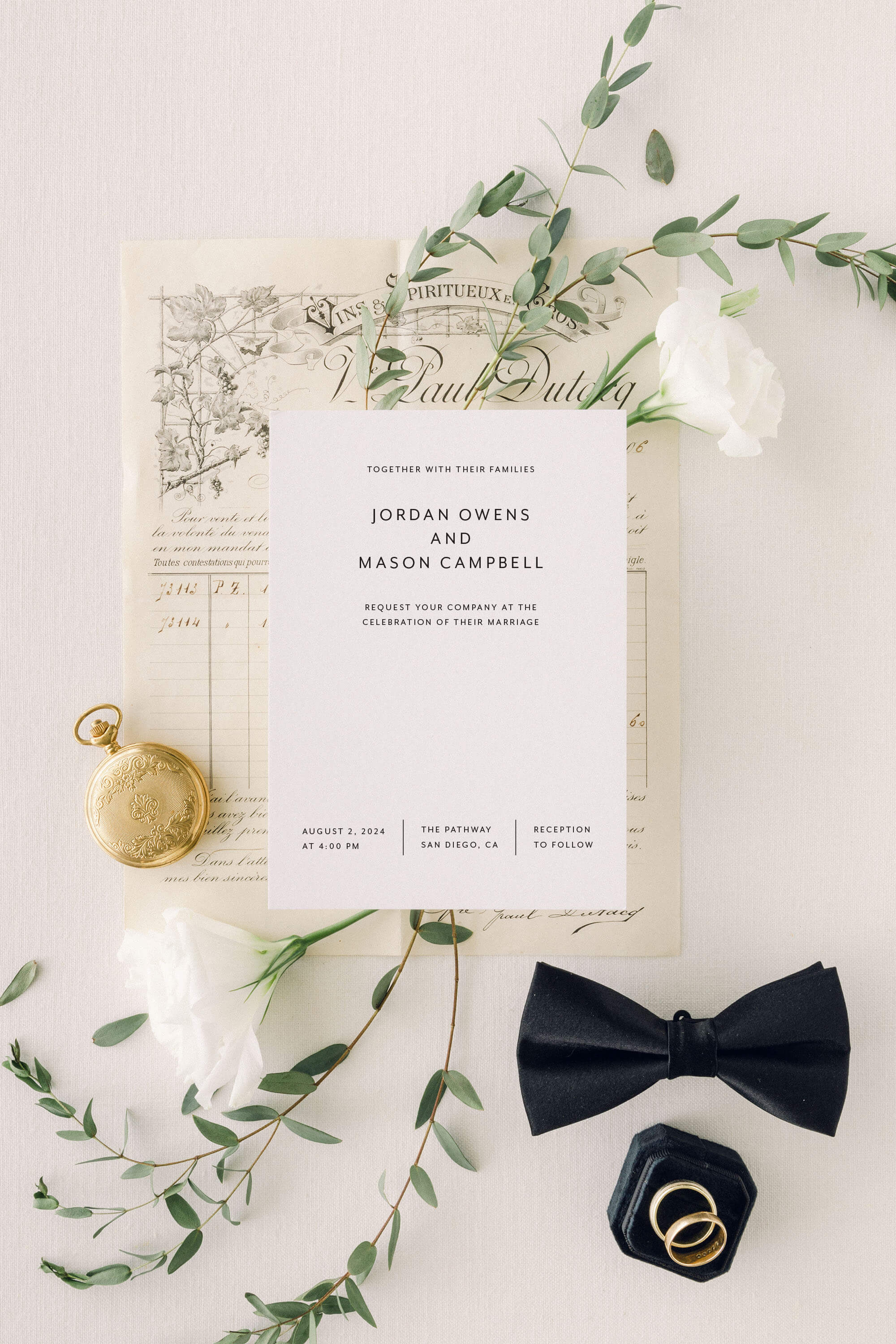 Simple Wedding invitation card with greenery, pocket watch, and black bow tie on a light background