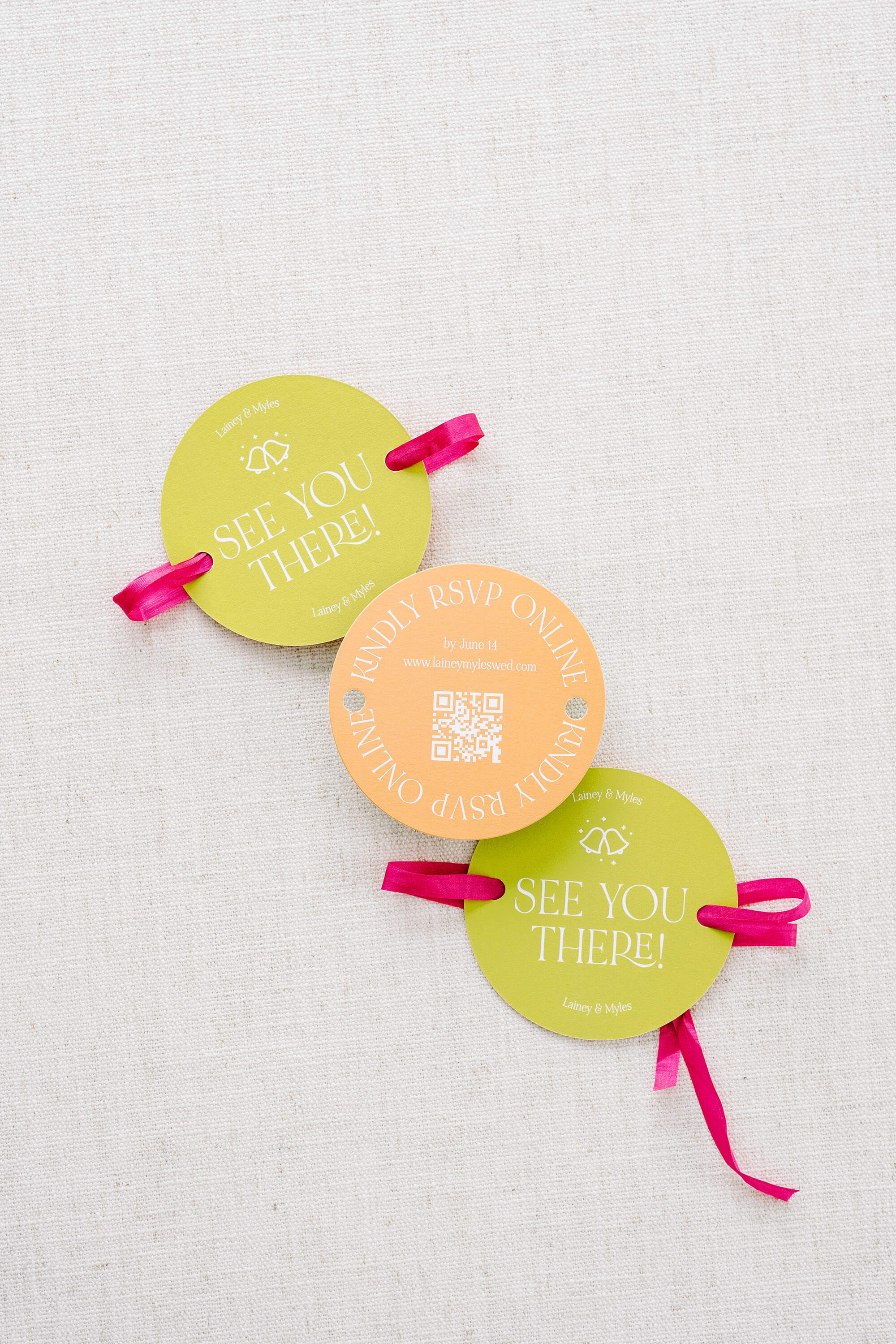 Three round rsvp cards with ribbons on a textured white background